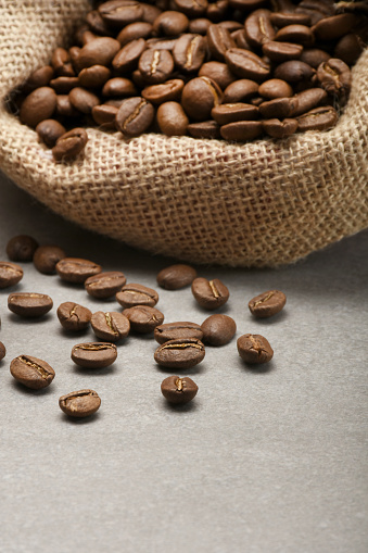 Roasted coffee beans scattered of the burlap bag on the stone background with copy space
