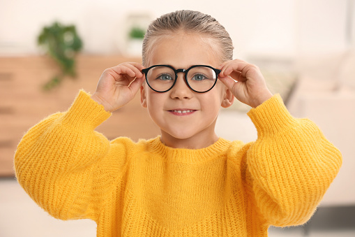 Portrait of cute little girl wearing glasses indoors