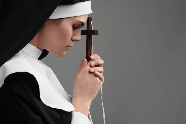 istock Nun with cross praying to God on grey background. Space for text 1496473597