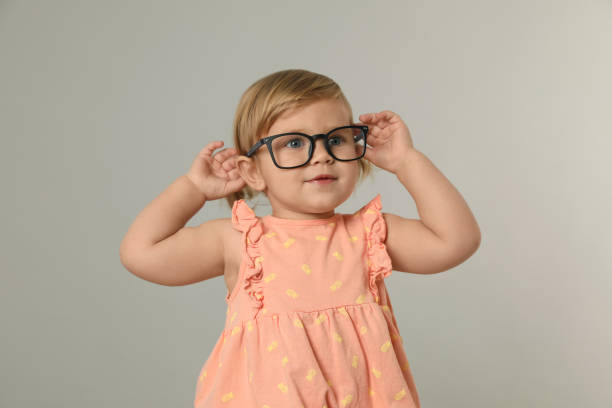 istock Cute little girl in glasses on light grey background 1496473646