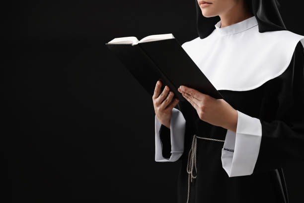 istock Nun reading Bible on black background, closeup. Space for text 1496473717