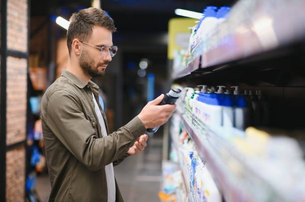 Smiling man chooses shampoo in supermarket
