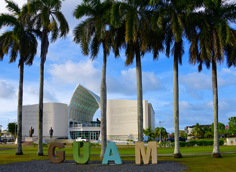Hagåtña / Agana, Guam: Guam sign on Plaza de España, framed by palm trees and in the background the book-like south façade of the Senator Antonio M. Palomo Guam Museum & Chamorro Educational Facility, a museum focusing on the history of Guam (architect Andrew Laguana).