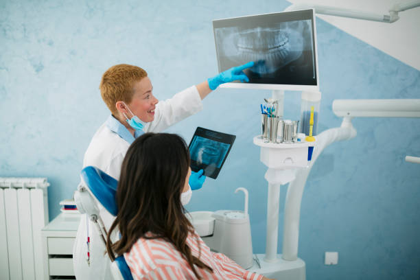 istock Female dentist explaining tooth x-rays to a patient 1496474768