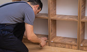 Managing carpentry business man in overalls assembling wooden rack