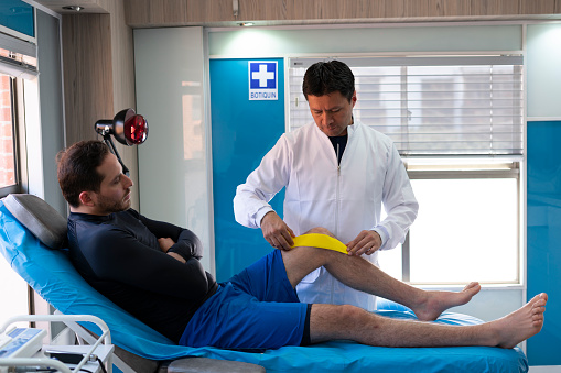 Physiotherapist doctor with his male patient, using appliances.