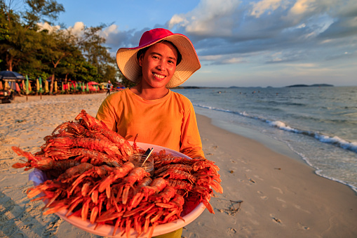 Happy Cambodian woman selling fresh lobsters on the beach, Sihanoukville, Cambodia