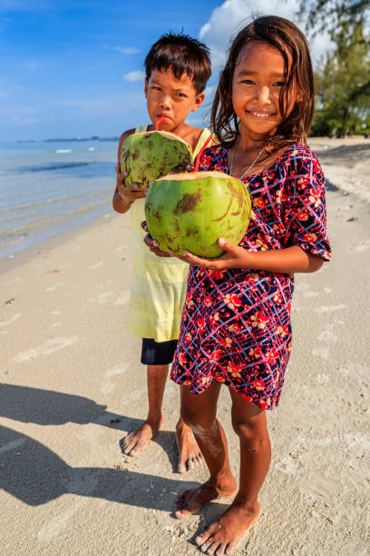 istock Cambodian children drinking coconut milk on the beach, Cambodia 1496477948