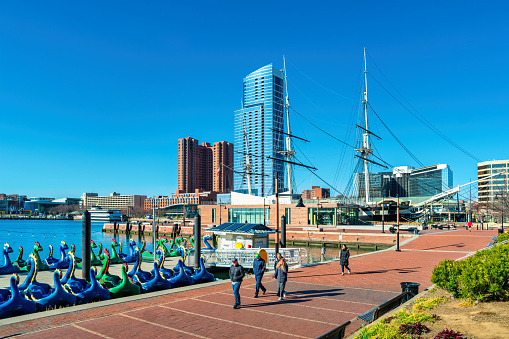 Pedestrians walk at the Inner Harbor in downtown Baltimore, Maryland, USA on a sunny day.