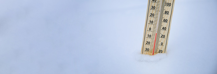 Wooden thermometer in fresh fluffy snow