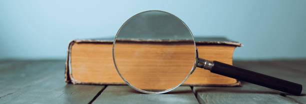 istock Book and magnifier on wooden table 1496480352