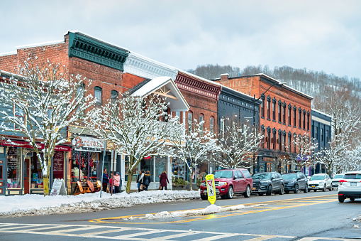 Pedestrians walk past stores in downtown Ellicottville, New York State, USA on an overcast day.