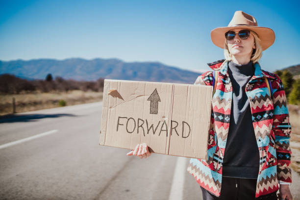 istock Going forward. Woman hitchhiking alone and holding a cardboard sign 1496481405