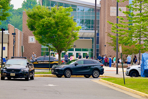 Fairfax, Virginia, USA - June 6, 2023: Parents, faculty and students gather outside the main entrance of Fairfax High School after a 911 call was received from the school. Police and first responders quickly convened on the property and the incident was resolved.