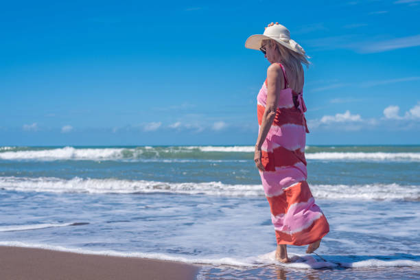 istock Mature woman relaxing during a walk at the beach. 1496494754