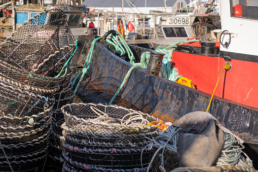 Prawn traps stacked on deck with the bow of a steel tugboat in the background