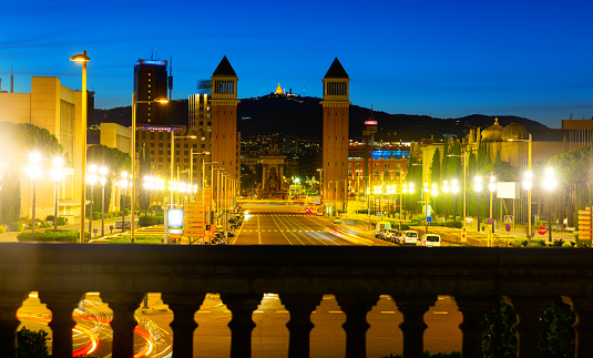 Picturesque Barcelona cityscape in summer twilight overlooking lighted avenue Avinguda de la Reina Maria Cristina with two Venetian Towers at junction with Placa dEspanya, Spain