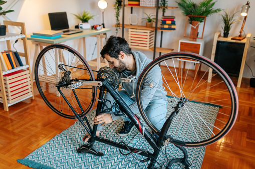 Focused young man repairing bicycle st home.