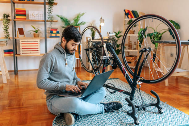 istock Man uses a laptop while repairing a bicycle 1496499349
