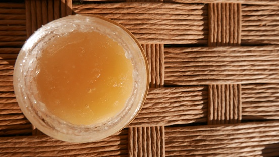 A jar of honey on the table, close-up shot. A small pot of honey in the sun. A honey pot, top view.