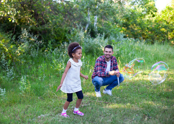 istock Happy father and daughter playing soap bubbles in park. 1496506652