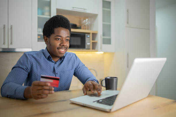 istock Cheerful man doing online shopping 1496507825