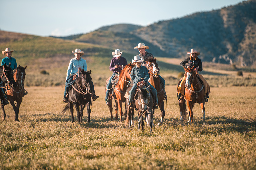 Sunny day of fun on the wild west. Caucasian community enjoying horse riding together while using matching cowboy hats.