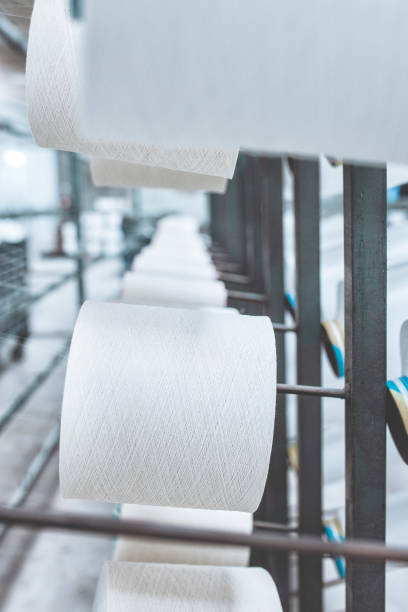 istock White yarn spools of industrial warping machine in textile factory 1496510793