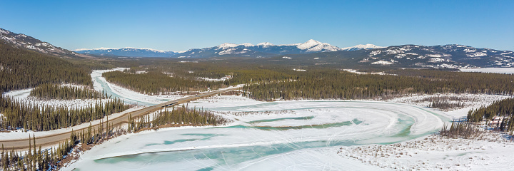 Spring time panoramic view in northern Canada with snow capped mountains over the Yukon River.