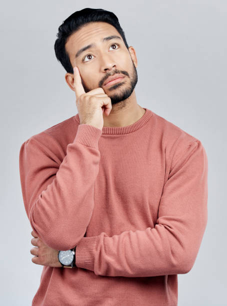 istock Thinking, confused and question with a man in studio on a gray background looking thoughtful or contemplative. Doubt, idea and memory with a young asian male trying to remember but feeling unsure 1496515128