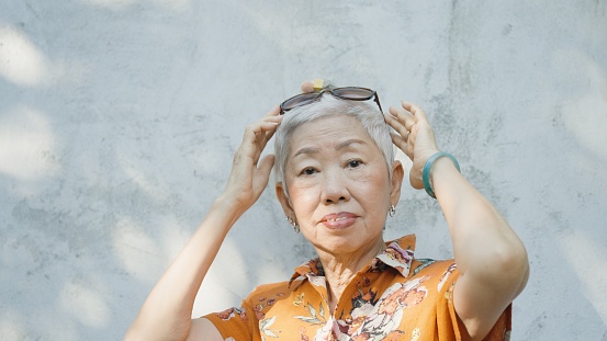 Active Asian senior woman with sunglasses in young at heart cool attitude