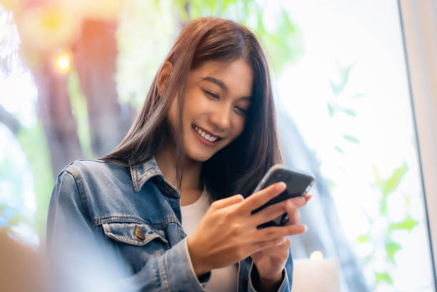 istock Young asian beautiful woman using smart phone in coffee shop cafe, typing write message on mobile, online shopping, transfer payment, internet banking 1496520632