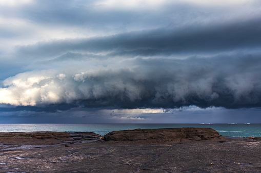 Dramatic shelf cloud storm system coming in to coast with onlookers. South Coast, NSW, Australia.