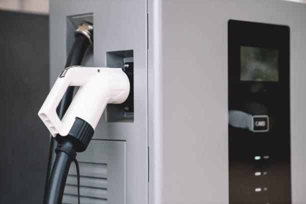 istock Close-Up electric car charging station. Plug for vehicle with electric engine. Charging point at car public parking lot. Future transport technology concept. EV charger. Clean energy for the world. 1496524095
