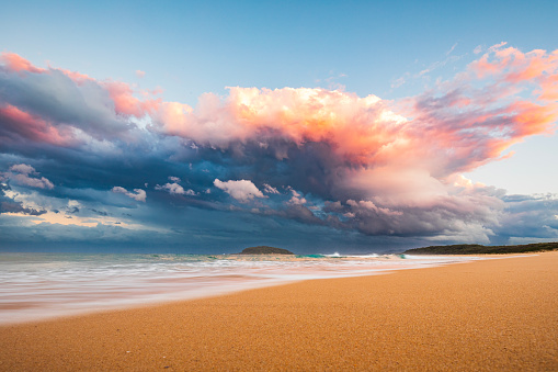 Coastal seascape of dramatic storm cell system over ocean illuminated by sunset. South Coast, NSW, Australia.