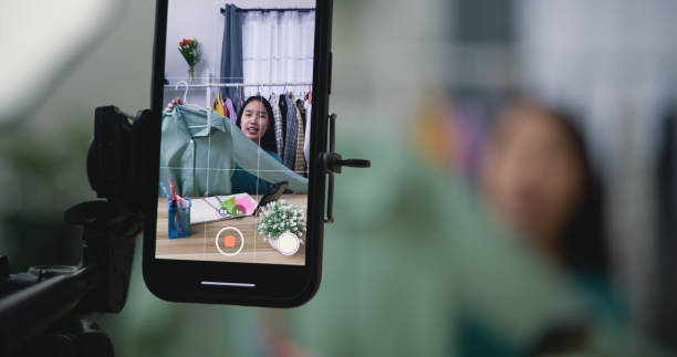 istock Young Asian female fashion designer using mobile phone live steaming 1496527486