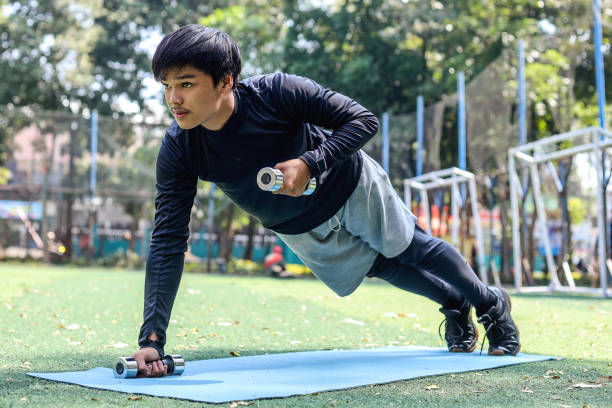 istock Young man exercising and doing push-ups outdoors on a barbell 1496531485