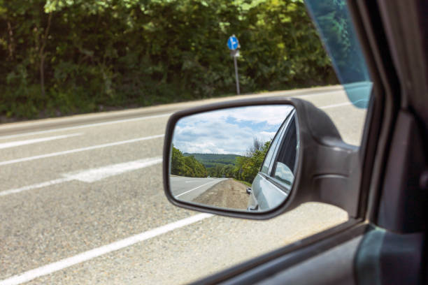 istock The view in the rearview mirror while driving down the road in the woods. 1496533172