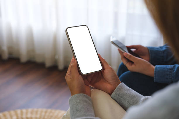 istock Mockup image of a couple woman holding and using a white mobile phone with blank desktop screen together 1496533783
