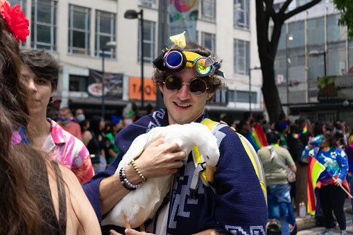 Mexico City, June 25th, 2022. Smiling young man carries duck at return of gay pride festival while celebrates.