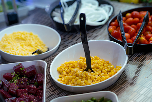 Salad bar. Salad buffet at restaurant. Fresh salad bar buffet for lunch. Healthy eating. Corn and purple sweet potato in bowl on counter. Vegetarian food. Self-service salad station in the restaurant.