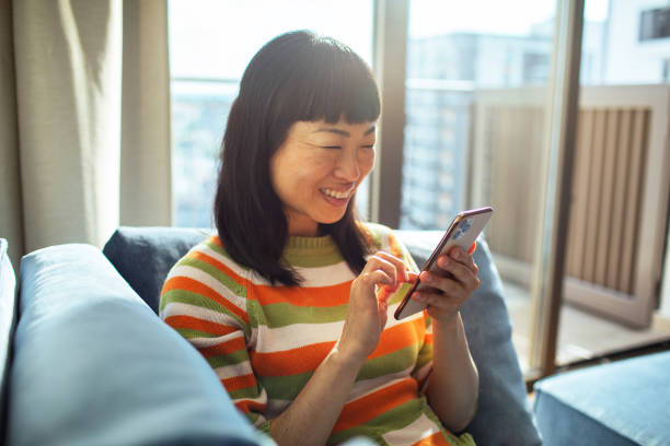 istock Young Japanese Woman using a smart phone at home 1496539459
