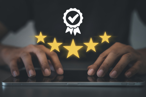 Close-up of man's hand rating service with gold star feedback icon on smartphone. Satisfaction survey, opinion and review concept for business success