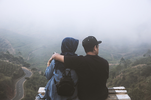 Rear view of couple traveler looking at fog of mountain