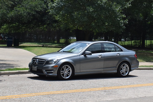 Houston, TX USA - Summer, June 6th, 2023 - Portrait of a silver Mercedes-Benz C-class as it cruises through Hermann Park in Houston