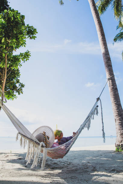 istock Woman holding coconut on hammock at the beach 1496542508