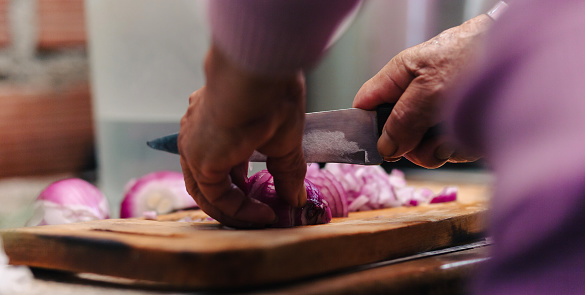 abuela en la cocina, cortando verduras, carnes y sazonando la comida, concepto de cocina tradicional y casera en Sudamérica.