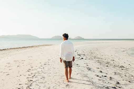 Young man walking on beach alone