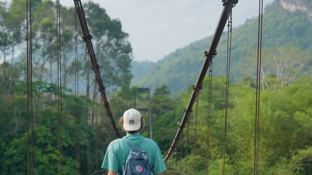 Man walking on suspension bridge in the jungles in Thailand