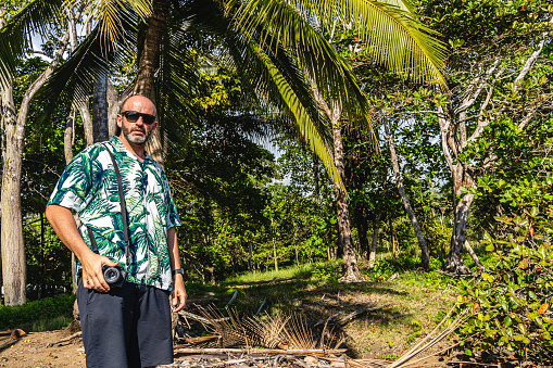 Photo with copy space of a man carrying a digital camera on a tropical surrounding